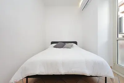 a white bed in a white bedroom with windows at Testaccio Sweet Holiday Apt in Rome