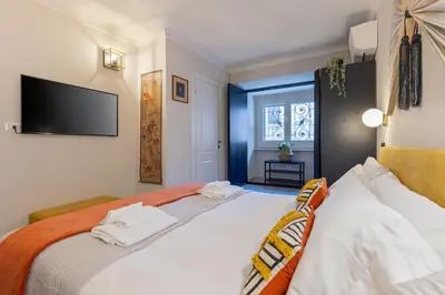 a bedroom with a bed with white sheets and a flat screen tv at Rome As You Feel - Charming Space at Torre Argentina in Rome