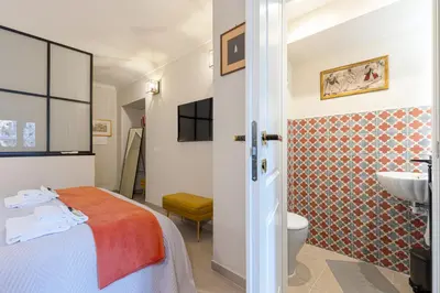a bedroom with a bed and a bathroom with a sink at Rome As You Feel - Charming Space at Torre Argentina in Rome