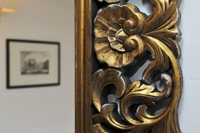 an ornate gold mirror on a wall with a picture at Rooftop view house near Piazza Navona in Rome