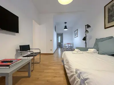 a living room with a bed and a table and a television at JHHIT - San Pietro First Suite in Rome
