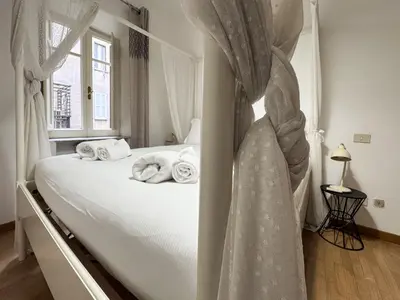 a bedroom with a bed with white sheets and a window at JHHIT - San Pietro First Suite in Rome