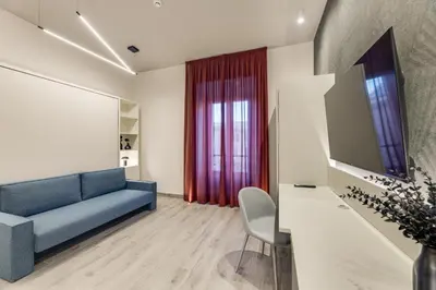 a living room with a blue couch and a tv at Belli Vatican Suites by Flatinrome in Rome