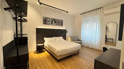 a bedroom with a bed and a chair and a television at Museum Hospitality - Vatican Apartments in Rome