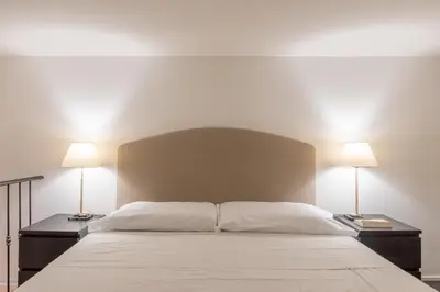 a bedroom with a large white bed with two lamps at iFlat Monti Studio Apartment in Rome