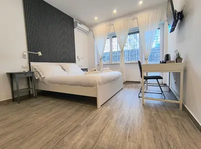 a bedroom with a bed and a desk and windows at San Pietro Experience in Rome