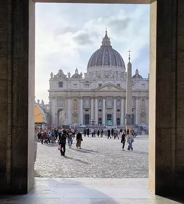 a group of people walking in front of a large building at San Pietro Experience in Rome