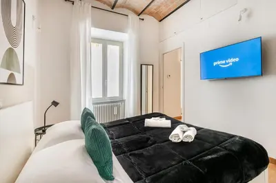 a black leather couch in a white room with a tv at V HOME Termini in Rome