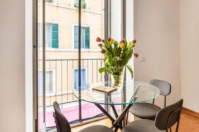 a glass table with chairs and a vase with flowers on it at V HOME Termini in Rome