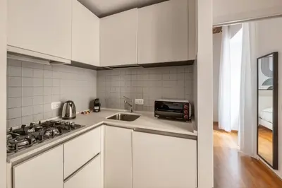 a white kitchen with a sink and a stove at V HOME Termini in Rome
