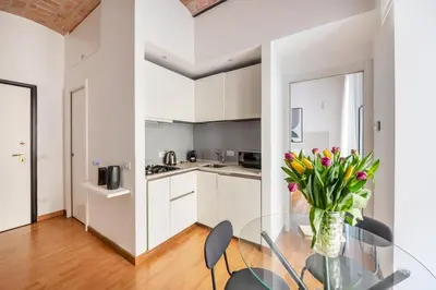 a kitchen with white cabinets and a glass table with flowers at V HOME Termini in Rome