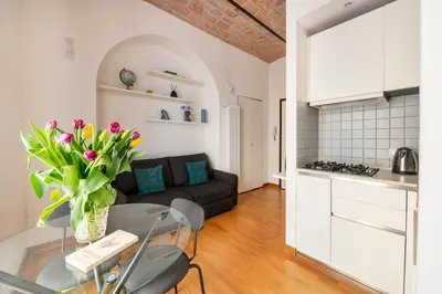 a kitchen and a living room with a glass table with flowers at V HOME Termini in Rome