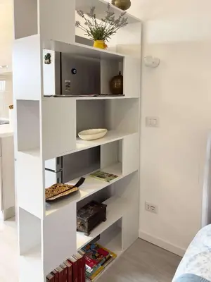 a white book shelf in a room with a tv at Domus Lucis Rome in Rome