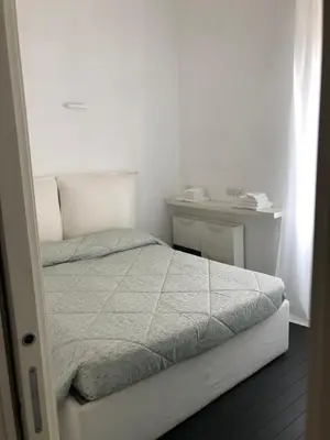 a white bedroom with a bed and a desk at Vatican 3th Floor in Rome