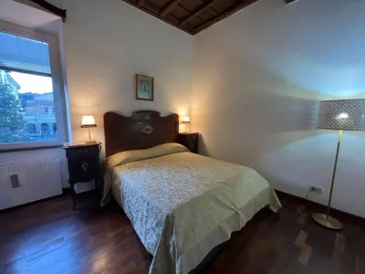 a bedroom with a bed and a lamp and a window at The Charm of Trastevere in Rome