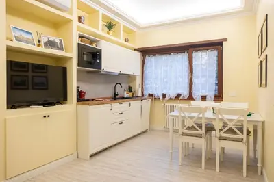 a kitchen with white cabinets and a table and chairs at Vatican House Crocifisso 51 in Rome
