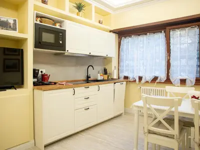 a kitchen with white cabinets and a dining table at Vatican House Crocifisso 51 in Rome