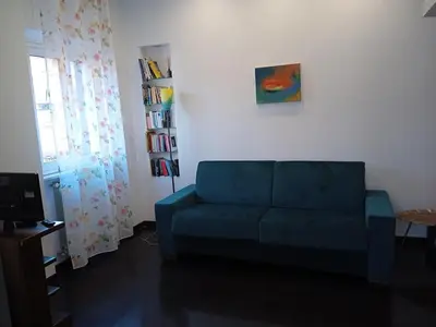 a living room with a blue couch and a window at Monolocale Aurelia in Rome