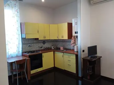 a small kitchen with yellow cabinets and a table at Monolocale Aurelia in Rome