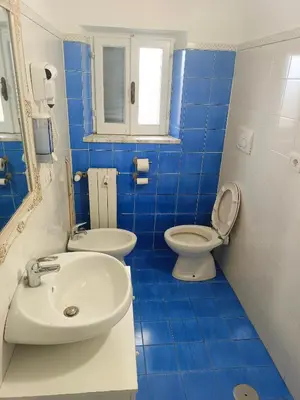a blue tiled bathroom with a sink and a toilet at Niam House in Rome