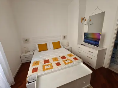 a white bedroom with a bed and a flat screen tv at Angolo Romano in Rome