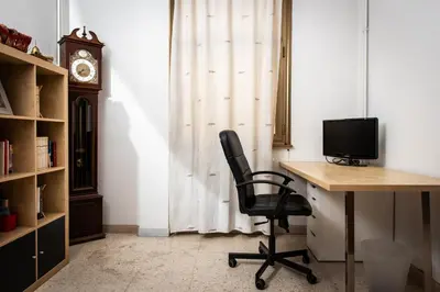 an office with a desk and a chair and a clock at Laterani36 elegante Appartamento 3 Camere, sopra Metro Porta Metronia in Rome