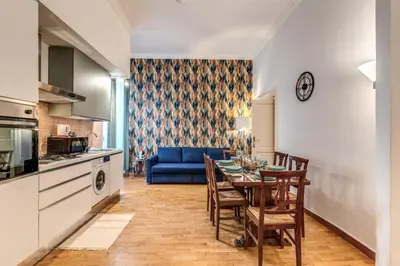 a kitchen and dining room with a table and a blue couch at Fresh House Ludovisi in Rome