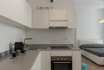 a kitchen with white cabinets and a sink and a bed at GuestHost - Ostiense Modern ApartamentS in Rome