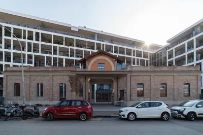a building with cars parked in a parking lot at GuestHost - Ostiense Modern ApartamentS in Rome
