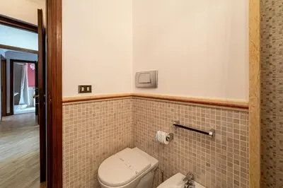 a bathroom with a toilet and a tiled wall at Margana Luxury 3 bedrooms amazing terrace in Rome