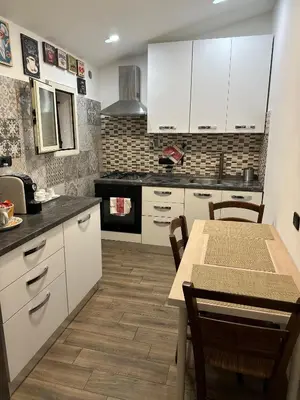 a kitchen with white cabinets and a table with chairs at Imperial Apartment in Rome