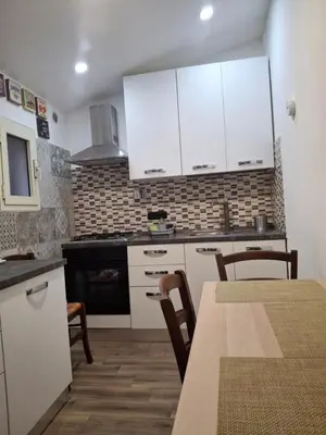 a kitchen with white cabinets and a table with chairs at Imperial Apartment in Rome