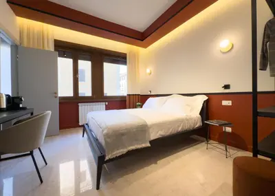 a bedroom with a bed and a desk and some windows at Vatican Domus Stefania Guest House in Rome