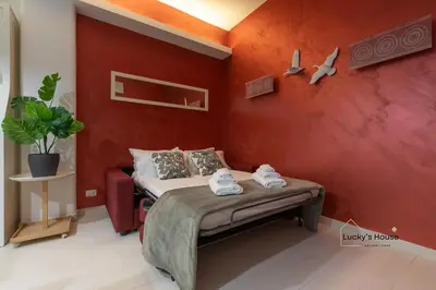 a bedroom with a bed in a red wall at Lucky's House - 400mt to Metro A, 3 bedrooms, 6-8 pax, A-C, Roma in Rome