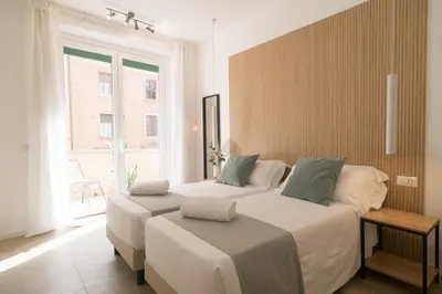 a bedroom with two beds and a large window at Lilla Suites - Musei Vaticani in Rome