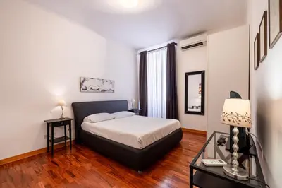 a bedroom with a bed and a table with a lamp at La Tua Casa al Colosseo in Rome