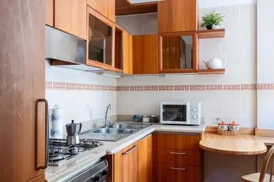 a kitchen with wooden cabinets and a sink and a microwave at La Tua Casa al Colosseo in Rome