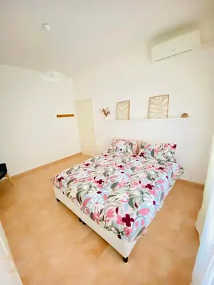 a white bedroom with a bed with a floral comforter at La Casa di Giada in Rome
