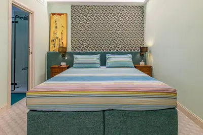 a bedroom with a large bed with a striped blanket at Tu chiamale emozioni intero appartamento in Rome
