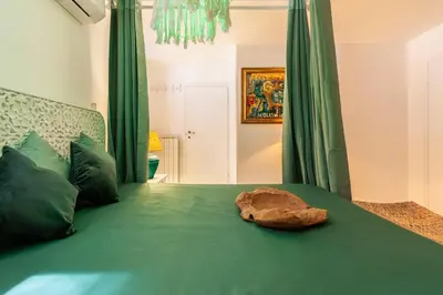 a bedroom with a green bed with a rock on it at Piazza Navona Loft for 7 people in Rome