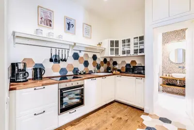 a kitchen with white cabinets and a wooden floor at Rome at Home in Rome