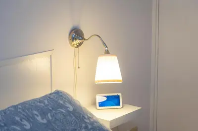a lamp on a bed with a clock on a night stand at Trastevere Relax by Rental in Rome in Rome