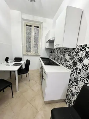 a kitchen and dining room with a table and a white kitchen at Apartment Dacia Colosseum in Rome