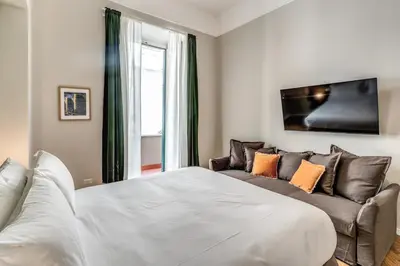 a bedroom with a white bed and a couch at DOWNTOWN SRL - The Great Court and The Great Chill in Rome