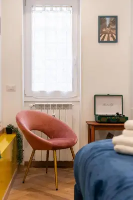 a chair in a room with a bed and a window at Casa Vacanze Ourplaces Sacchetti in Rome