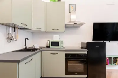 a kitchen with white cabinets and a black refrigerator at Casa Vacanze Ourplaces Sacchetti in Rome