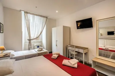 a bedroom with two beds and a desk and a mirror at GuestHouse o Affittacamere La civetta di Trastevere in Rome