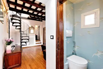a bathroom with a toilet and a spiral staircase at Trastevere Penthouse amazing terrace in Rome