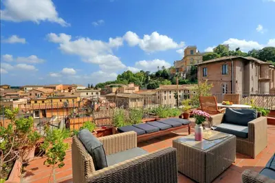 a patio with wicker furniture and a view of the city at Trastevere Penthouse amazing terrace in Rome