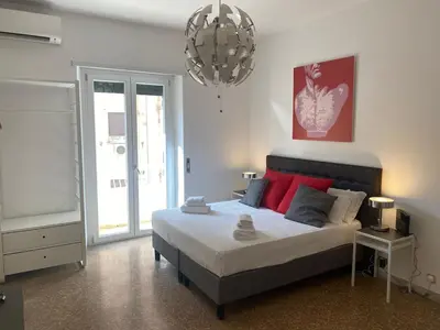 a bedroom with a bed with red pillows and a chandelier at Clodio Apartment in Rome